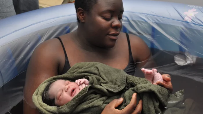 mother in birthing pool holding her newborn