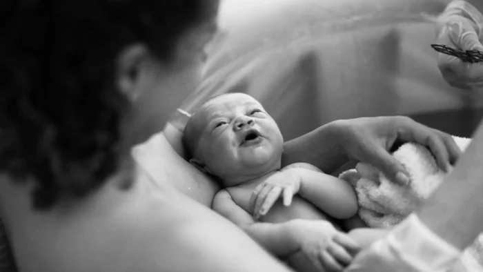 mother in birthing pool looking at her new born baby